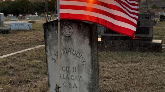 PHOTO BY ERIC ANDERSON At sunset, a flag waves over a gravestone at Phillips Cemetery.