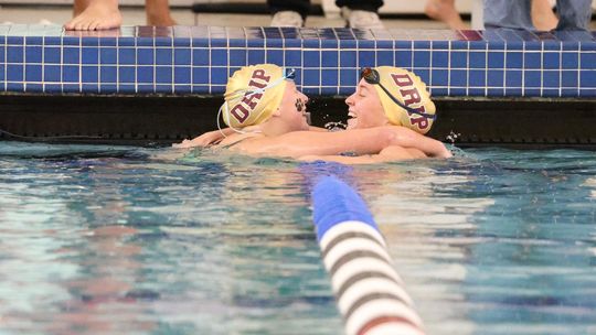 PHOTO BY JEFF MAY Junior Kylie May and senior Abigail Owens], teammates and close friends, celebrate after both swimming personal best times in the Girls 200 Yard Individual Medley.