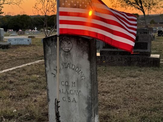 PHOTO BY ERIC ANDERSON At sunset, a flag waves over a gravestone at Phillips Cemetery.