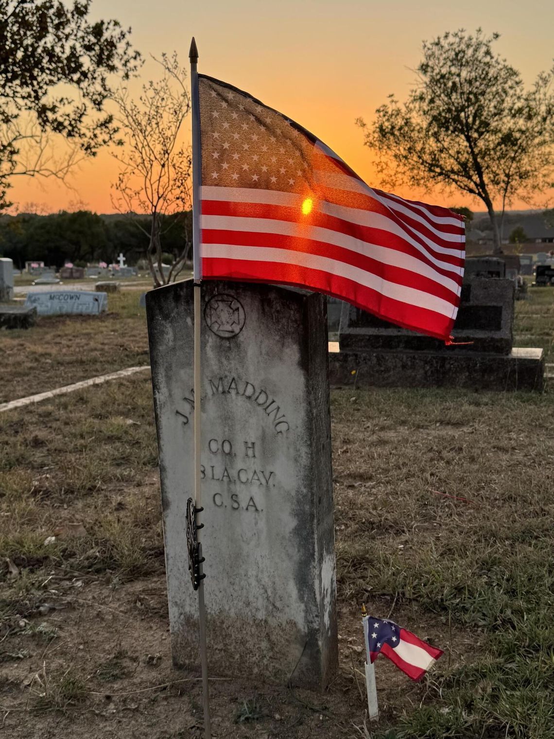 PHOTO BY ERIC ANDERSON At sunset, a flag waves over a gravestone at Phillips Cemetery.