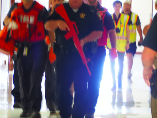 A security force escorts the first group of North Hays Fire/Rescue and EMS (medical support) personnel into the building.