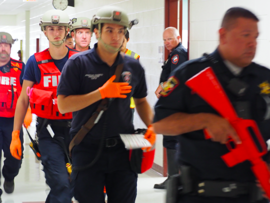 A security force escorts the second group of North Hays Fire/Rescue and EMS (medical support) personnel into the building.