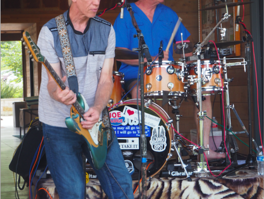 “Black Cat Choir” John Holmes played lead guitar, with drummer Jay Robinson behind him, during the car show.