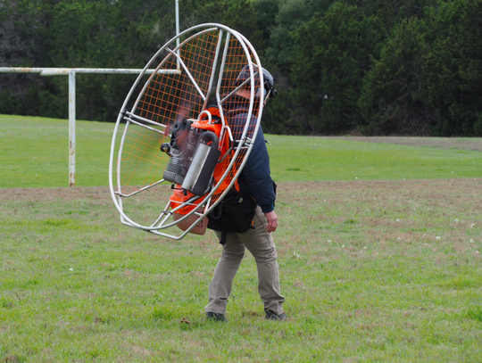 With the engine fan on, Reynold cautiously walks towards his paraglider assembly, which  he had previously already laid out.