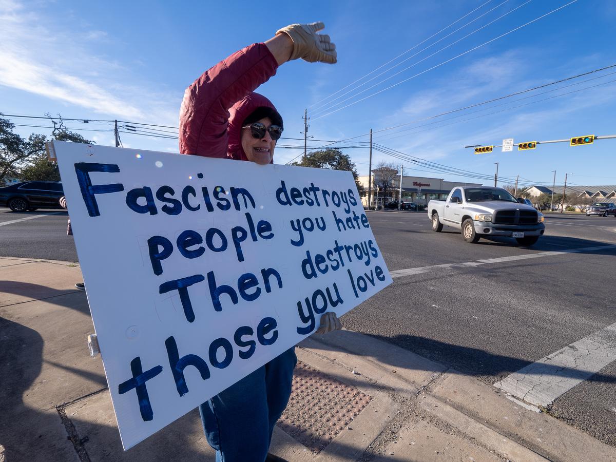 PHOTO BY DAVE WILSON A protestor waves to passing cars.