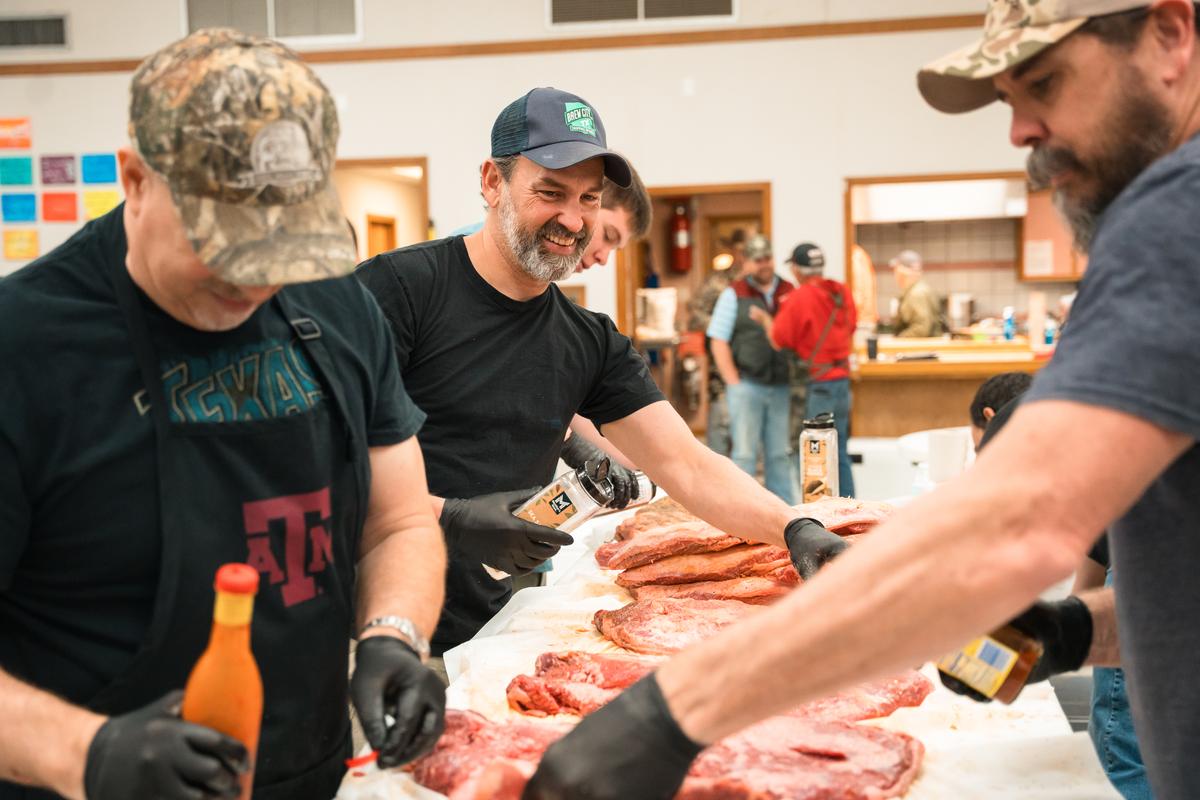 PHOTO COURTESY OF TALIA WADE Volunteers season the meat on prep day.