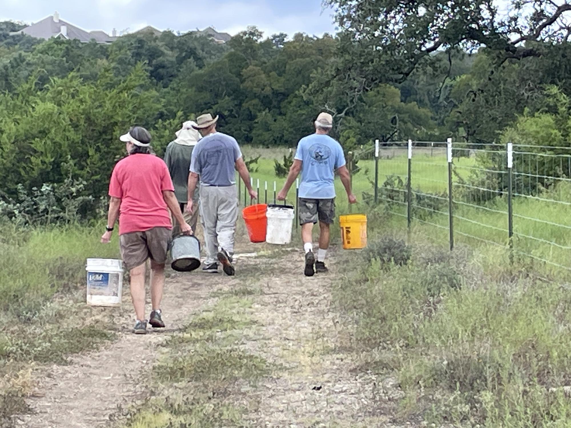 Hays County Master Naturalists carry buckets to water the trees. PHOTO BY TIN...