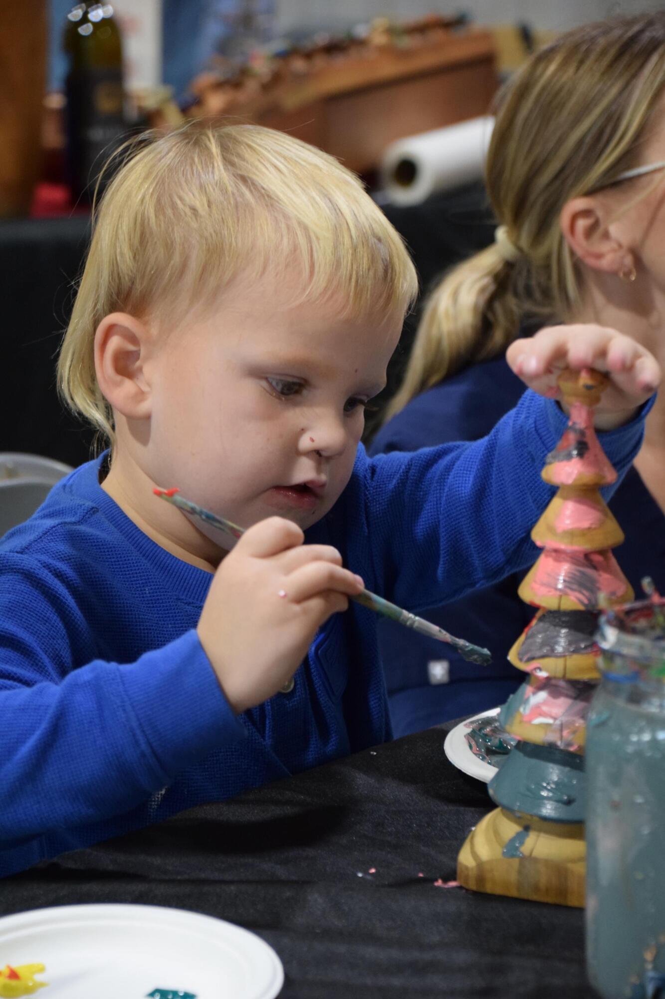 PHOTO BY LAURIE ANDERSON A kid decorates a wooden Christmas tree at the Tolly...