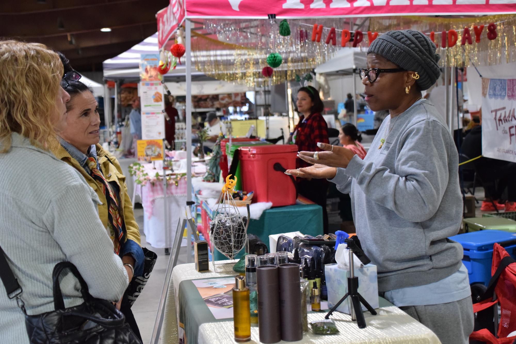 PHOTO BY LAURIE ANDERSON During a December market, a vendor talks to her cust...
