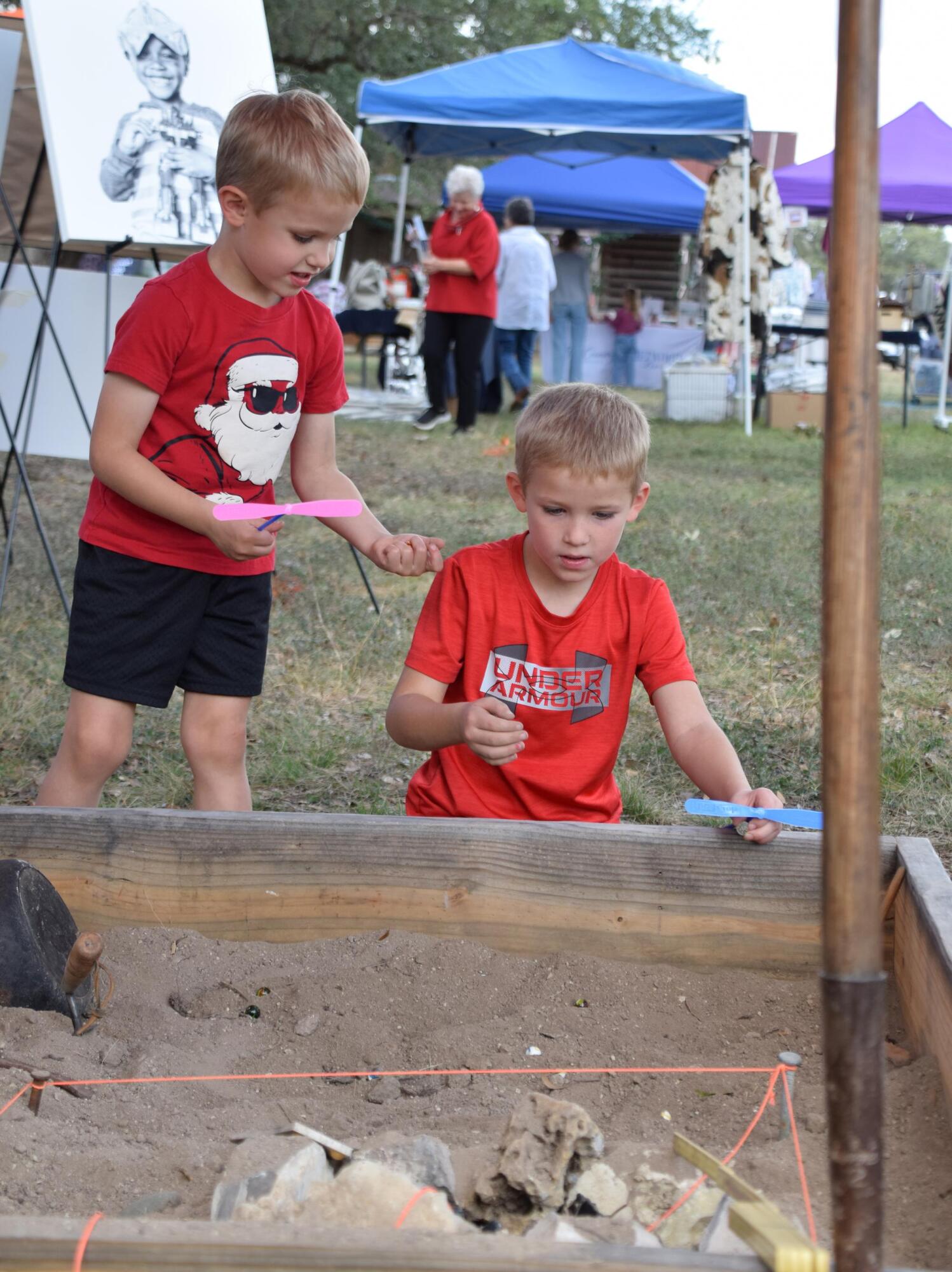 PHOTO BY LAURIE ANDERSON Boys check out a “dig” at the booth of archeologist...