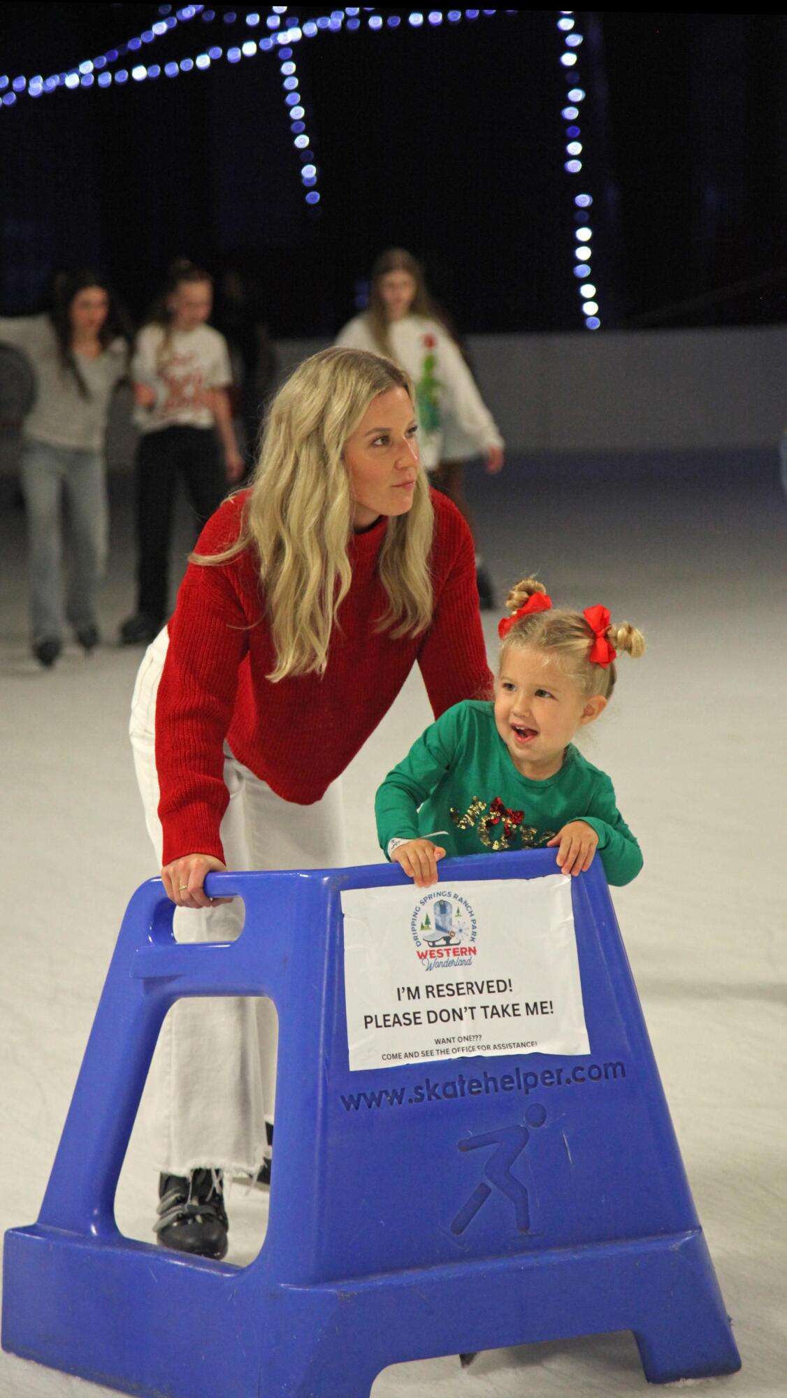 A young skater enjoys the rink with a little help.